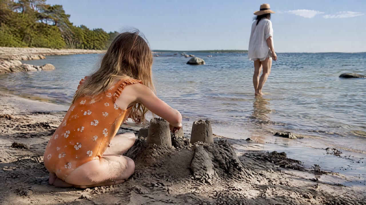 Barn bygger sandslott vid grunt vatten vid stranden